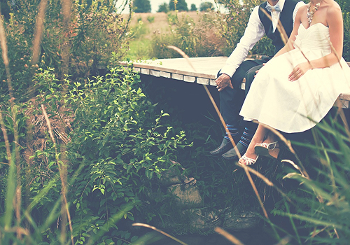 自然の中にある橋の淵にカップルが座っている画像