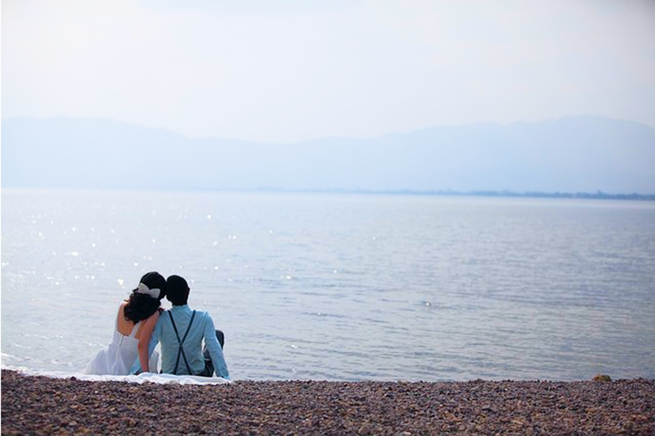 浜辺でカップルが座って海を眺めて画像