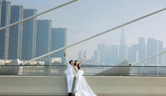 橋の上で腕を上げている新郎新婦の画像