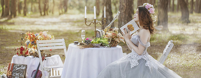 森の中でテーブルを前にほくそ笑む新婦の画像
